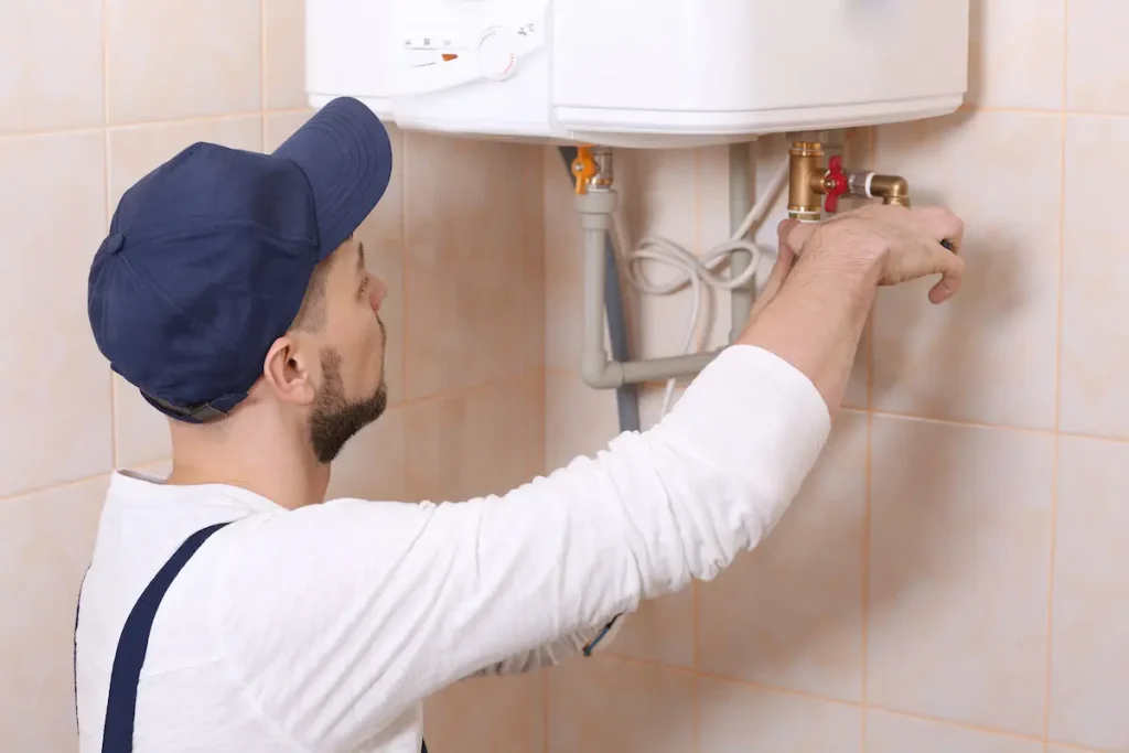 Plumber installing water heater on a tiled wall